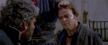 Movie still from “For a Few Dollars More” (1965), directed by Sergio Leone – A man is combing another man's hair in a scene; Close Up shot, Over the shoulder angle