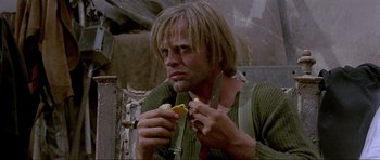 Movie still from “For a Few Dollars More” (1965), directed by Sergio Leone – A man eating a sandwich while holding a knife in his hand; Close Up shot, Low angle