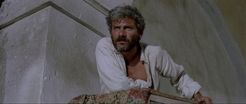 Movie still from “For a Few Dollars More” (1965), directed by Sergio Leone – A man in a white shirt is leaning against a wall; Close Up shot, Low angle