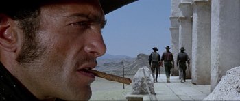 Movie still from “For a Few Dollars More” (1965), directed by Sergio Leone – A man eating a hot dog while walking down a street; Close Up shot, Low angle