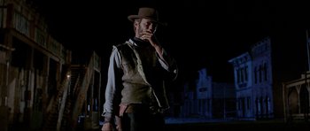 Movie still from “For a Few Dollars More” (1965), directed by Sergio Leone – A man with a gun standing in the dark; Medium shot, Low angle