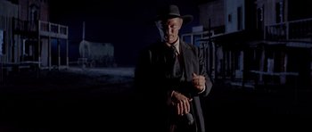 Movie still from “For a Few Dollars More” (1965), directed by Sergio Leone – A man in a suit and a hat holding a gun; Medium shot, Low angle