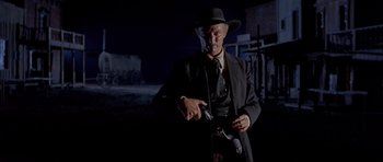 Movie still from “For a Few Dollars More” (1965), directed by Sergio Leone – A man wearing a hat and a suit holding a gun; Medium shot, Low angle