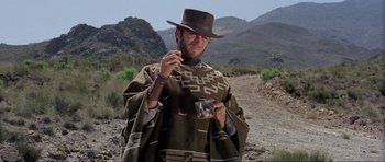 Movie still from “For a Few Dollars More” (1965), directed by Sergio Leone – A man in a cowboy hat holding up a picture; Medium shot, Low angle