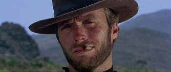 Movie still from “For a Few Dollars More” (1965), directed by Sergio Leone – A person wearing a hat and smoking a cigarette; Close Up shot, Low angle