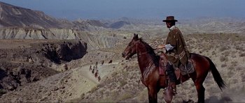 Movie still from “For a Few Dollars More” (1965), directed by Sergio Leone – A man riding a horse in the desert; Wide shot, High angle