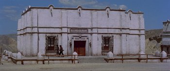 Movie still from “For a Few Dollars More” (1965), directed by Sergio Leone – A person walking in front of an old building; Extreme Wide shot, Low angle