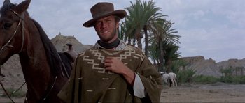 Movie still from “For a Few Dollars More” (1965), directed by Sergio Leone – A man wearing a hat and a poncho in the desert; Medium shot, Low angle