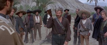 Movie still from “For a Few Dollars More” (1965), directed by Sergio Leone – A group of men standing on top of a sandy beach; Medium shot, Low angle