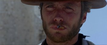 Movie still from “For a Few Dollars More” (1965), directed by Sergio Leone – A person with a hat smoking a cigarette; Close Up shot, Low angle
