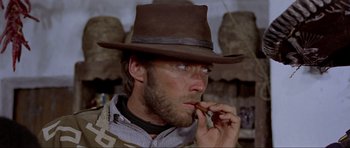 Movie still from “For a Few Dollars More” (1965), directed by Sergio Leone – A man wearing a brown hat talking on a cell phone; Close Up shot, Low angle