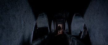 Movie still from “For a Few Dollars More” (1965), directed by Sergio Leone – A man walking through a tunnel in the dark; Extreme Wide shot, Low angle