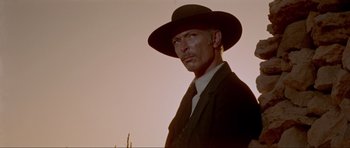 Movie still from “For a Few Dollars More” (1965), directed by Sergio Leone – A man wearing a suit and a cowboy hat; Close Up shot, Low angle