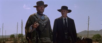 Movie still from “For a Few Dollars More” (1965), directed by Sergio Leone – A man and a man in a suit and hat; Medium shot, Low angle