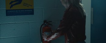 Movie still from “Freaky” (2020), directed by Christopher Landon – A man in a red jacket is putting a fire extinguisher on a fire hydrant; Extreme Close Up shot, Over the shoulder angle