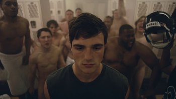 Movie still from “Euphoria” (2019), created by Sam Levinson – A group of shirtless men standing in a room with a man in a black tank top; Medium shot, High angle
