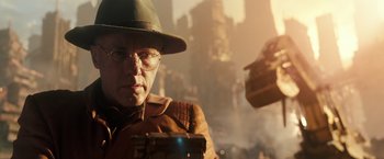 Movie still from “Alita: Battle Angel” (2019), directed by Robert Rodriguez – A man in a hat and glasses looking at a cell phone; Close Up shot, Over the shoulder angle