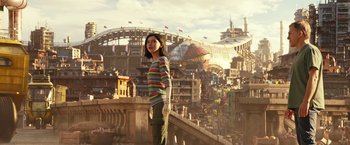Movie still from “Alita: Battle Angel” (2019), directed by Robert Rodriguez – A woman standing on top of a building in front of a city; Wide shot, Over the shoulder angle