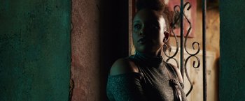 Movie still from “Alita: Battle Angel” (2019), directed by Robert Rodriguez – A woman in a green top is standing by a brick wall; Close Up shot, Low angle