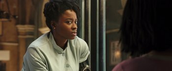 Movie still from “Alita: Battle Angel” (2019), directed by Robert Rodriguez – A woman sitting on top of a chair in front of a window; Close Up shot, Over the shoulder angle