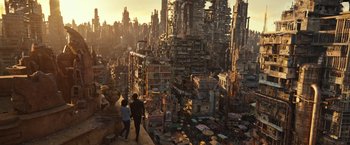 Movie still from “Alita: Battle Angel” (2019), directed by Robert Rodriguez – Two people are standing on a ledge looking over a city; Extreme Wide shot, High angle