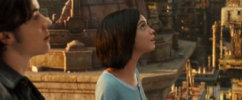 Movie still from “Alita: Battle Angel” (2019), directed by Robert Rodriguez – A woman with short black hair looking upward; Close Up shot, Over the shoulder angle