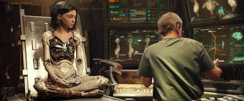 Movie still from “Alita: Battle Angel” (2019), directed by Robert Rodriguez – A woman and a man are sitting in front of computer screens; Medium shot, Over the shoulder angle