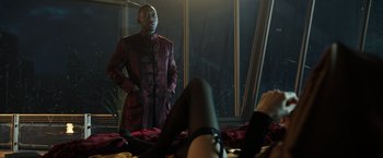 Movie still from “Alita: Battle Angel” (2019), directed by Robert Rodriguez – A man standing in front of a window with his hands in his pockets; Medium shot, Over the shoulder angle