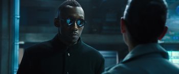 Movie still from “Alita: Battle Angel” (2019), directed by Robert Rodriguez – A man in a black jacket and sunglasses; Close Up shot, Over the shoulder angle