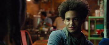 Movie still from “Alita: Battle Angel” (2019), directed by Robert Rodriguez – A young man with a curly afro is posing for a picture; Close Up shot, Over the shoulder angle