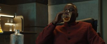 Movie still from “Alita: Battle Angel” (2019), directed by Robert Rodriguez – A man in a red jacket drinking from a glass; Close Up shot, High angle