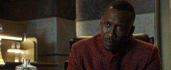 Movie still from “Alita: Battle Angel” (2019), directed by Robert Rodriguez – A person sitting in a chair wearing a jacket; Close Up shot, Over the shoulder angle