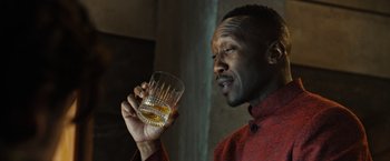 Movie still from “Alita: Battle Angel” (2019), directed by Robert Rodriguez – A man holding up a glass of whiskey; Close Up shot, Low angle