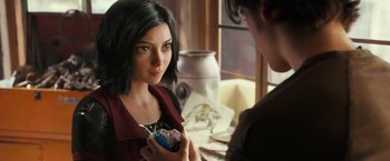 Movie still from “Alita: Battle Angel” (2019), directed by Robert Rodriguez – A woman holding a cell phone in her hand; Close Up shot, Over the shoulder angle