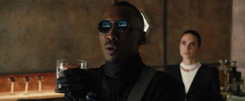 Movie still from “Alita: Battle Angel” (2019), directed by Robert Rodriguez – A man wearing sunglasses and holding a drink; Close Up shot, Low angle