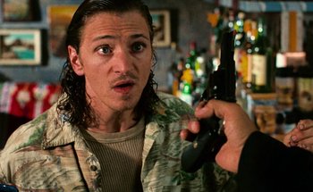 Movie still from “From Dusk Till Dawn” (1996), directed by Robert Rodriguez – A man holding a gun up to his face; Close Up shot, Over the shoulder angle