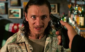 Movie still from “From Dusk Till Dawn” (1996), directed by Robert Rodriguez – A man holding a gun up to his face; Close Up shot, Low angle