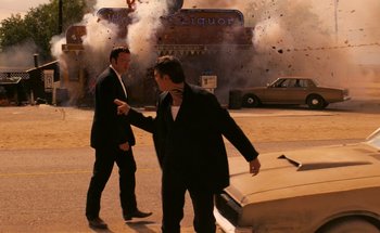 Movie still from “From Dusk Till Dawn” (1996), directed by Robert Rodriguez – A couple of men walking down a street near a building; Wide shot, Over the shoulder angle