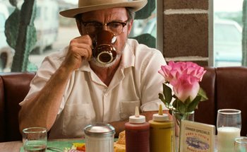 Movie still from “From Dusk Till Dawn” (1996), directed by Robert Rodriguez – An older man sitting at a table drinking coffee; Close Up shot, Over the shoulder angle