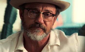 Movie still from “From Dusk Till Dawn” (1996), directed by Robert Rodriguez – An older man wearing glasses and a hat; Close Up shot, Over the shoulder angle