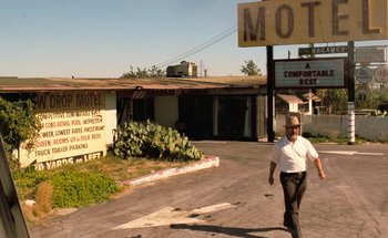 Movie still from “From Dusk Till Dawn” (1996), directed by Robert Rodriguez – A man walking down the street in front of a motel; Wide shot, Low angle