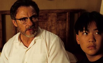 Movie still from “From Dusk Till Dawn” (1996), directed by Robert Rodriguez – A man and a young boy sitting next to each other in a room; Close Up shot, Over the shoulder angle