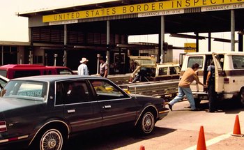 Movie still from “From Dusk Till Dawn” (1996), directed by Robert Rodriguez – A car parked in front of a building with people walking around; Wide shot, Low angle