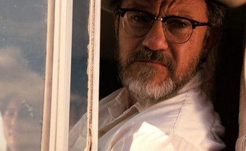 Movie still from “From Dusk Till Dawn” (1996), directed by Robert Rodriguez – An older man wearing glasses looking out of a window; Close Up shot, Low angle