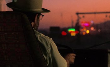Movie still from “From Dusk Till Dawn” (1996), directed by Robert Rodriguez – A man wearing a hat sitting in the driver's seat of a car; Close Up shot, Over the shoulder angle
