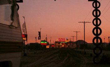Movie still from “From Dusk Till Dawn” (1996), directed by Robert Rodriguez – A dirt road that has a lot of neon signs on it; Extreme Wide shot, Low angle