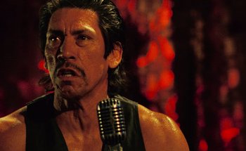 Movie still from “From Dusk Till Dawn” (1996), directed by Robert Rodriguez – A person holding a microphone; Close Up shot, Low angle