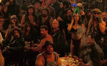 Movie still from “From Dusk Till Dawn” (1996), directed by Robert Rodriguez – A group of people gathered around a table with food; Wide shot, High angle