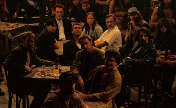 Movie still from “From Dusk Till Dawn” (1996), directed by Robert Rodriguez – A group of people sitting around a table; Wide shot, High angle