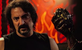 Movie still from “From Dusk Till Dawn” (1996), directed by Robert Rodriguez – A man in a black tank top holding a black glove; Close Up shot, Over the shoulder angle